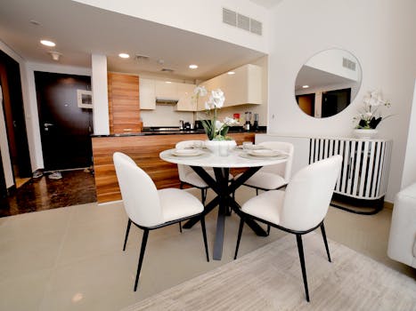 Bright and sleek kitchen with dining setup featuring modern decor and elegant furnishings.